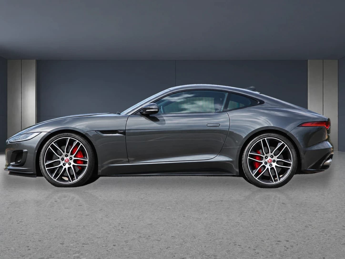 Prepared gray Jaguar F-Type in a neutral showroom from the side