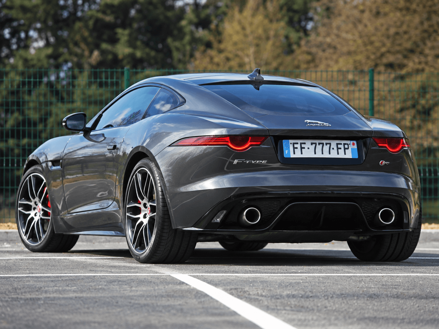 Unprepared gray Jaguar F-Type photographed from the rear three-quarter outdoors