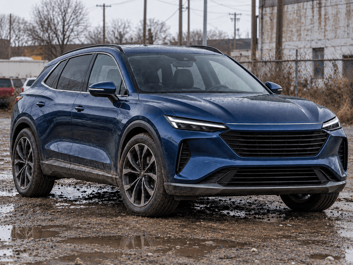 Unprepared dark blue SUV photographed outdoors on a wet industrial lot